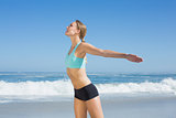 Fit woman standing on the beach with arms out