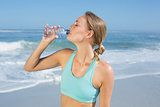 Fit woman standing on the beach taking a drink