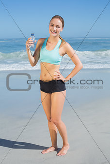 Fit woman standing on the beach holding water bottle