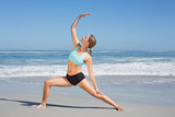 Fit woman standing on the beach in warrior pose