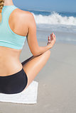 Fit woman sitting on the beach in lotus pose