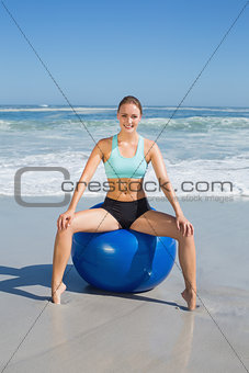 Fit woman sitting on exercise ball at the beach