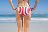 Lower rear view of fit woman in striped bikini at beach