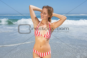 Blonde fit woman in striped bikini at beach smiling