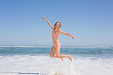 Happy fit woman in bikini jumping on the beach