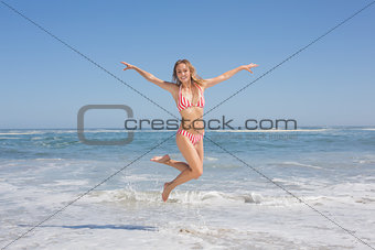 Happy fit woman in bikini jumping on the beach