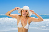Smiling blonde in white bikini and sunhat on the beach