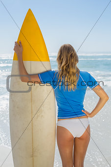 Blonde surfer holding her board on the beach