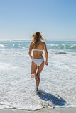 Gorgeous blonde in white bikini running to the sea