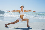 Gorgeous blonde in warrior pose by the sea