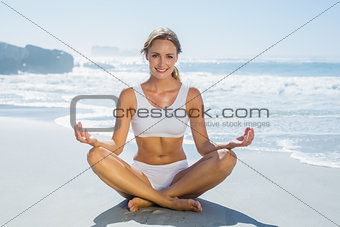 Gorgeous blonde in lotus pose by the sea