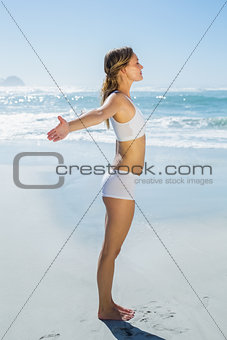 Gorgeous blonde standing with arms out by the sea