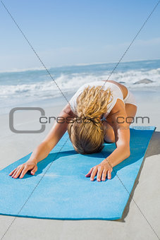 Gorgeous fit blonde in childs pose on the beach