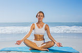Fit calm woman sitting in lotus pose on the beach
