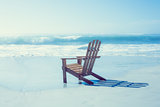 Wooden deck chair in the sand by the sea