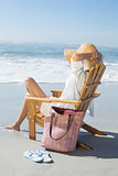 Woman sitting on wooden deck chair by the sea