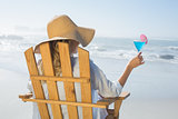 Woman relaxing in deck chair by the sea holding cocktail