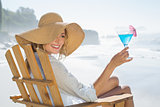 Woman relaxing in deck chair by the sea holding cocktail