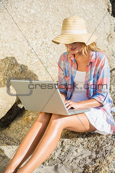 Pretty blonde using laptop at the beach