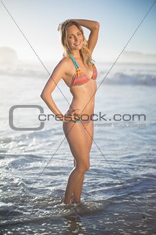 Happy blonde standing in the sea posing in bikini