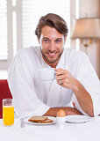 Handsome man having breakfast in his bathrobe