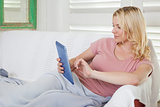 Pretty blonde lying on couch using tablet pc