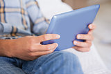 Man lying on couch using tablet pc