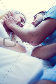 Couple lying on bed smiling at each other