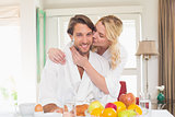 Cute couple in bathrobes having breakfast together