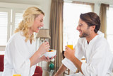 Cute couple in bathrobes having breakfast together
