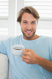 Handsome casual man sitting on couch having coffee