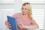 Happy blonde relaxing on the couch with her tablet pc