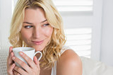 Happy blonde relaxing on the couch with a coffee