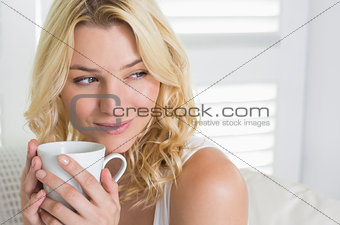 Happy blonde relaxing on the couch with a coffee