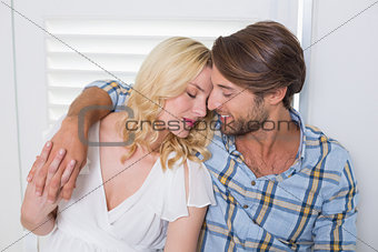 Cute young couple sitting on floor together holding hands