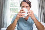 Handsome man sitting on bed drinking coffee