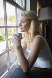 Pretty blonde sitting by the window having coffee