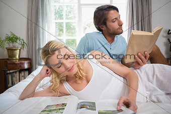 Couple relaxing on bed reading books