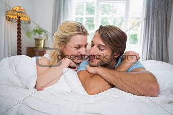 Cute couple relaxing on bed smiling at each other