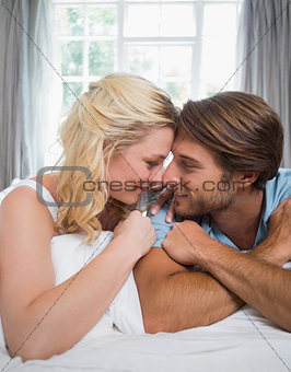 Cute couple relaxing on bed smiling at each other