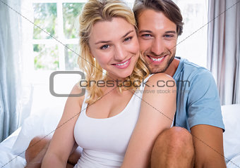 Cute young couple relaxing on bed smiling at camera