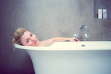 Serene blonde lying in the bath smiling at camera