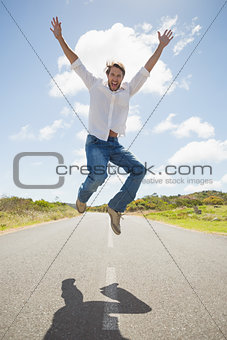 Handsome casual man leaping on a road smiling at camera
