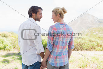 Cute couple standing hand in hand smiling at each other