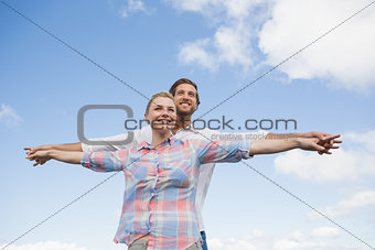 Happy couple standing outside with arms stretched