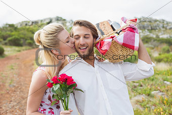 Cute couple going for a picnic with woman kissing boyfriends cheek