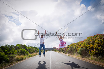 Excited couple jumping on the road