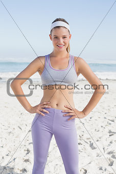 Sporty blonde on the beach smiling at camera
