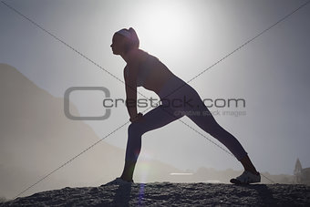 Sporty blonde stretching on the beach on a rock