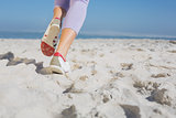 Sporty womans feet jogging on the sand
